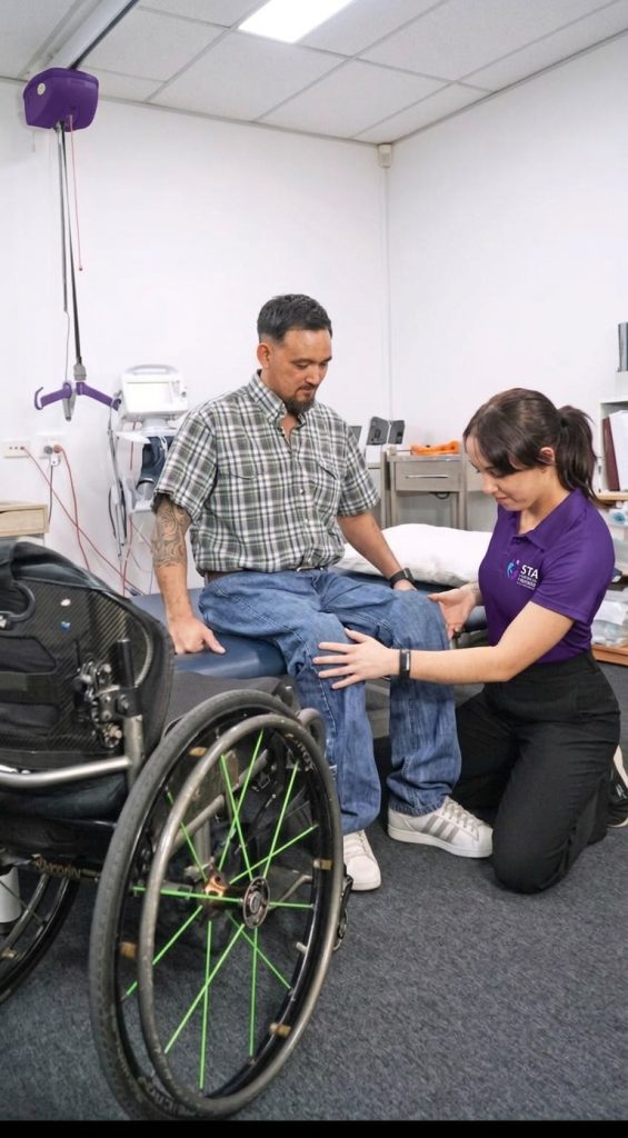 STA allied health clinician assessing a client's knee mobility in clinic