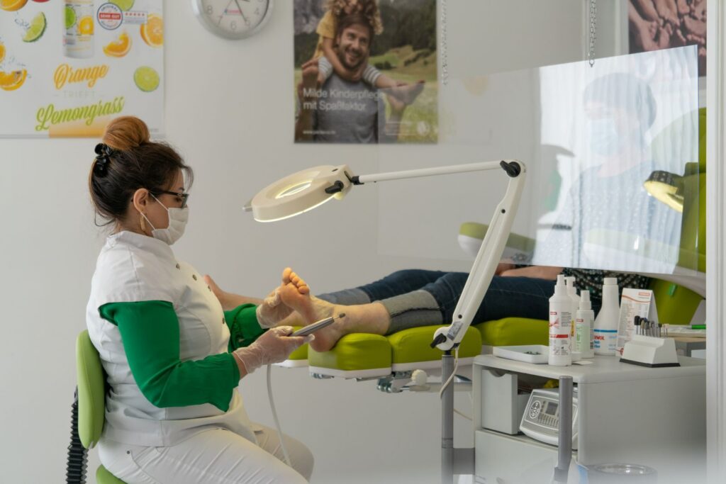 A clinician wearing a mask treating a patient's foot in a bright clinic