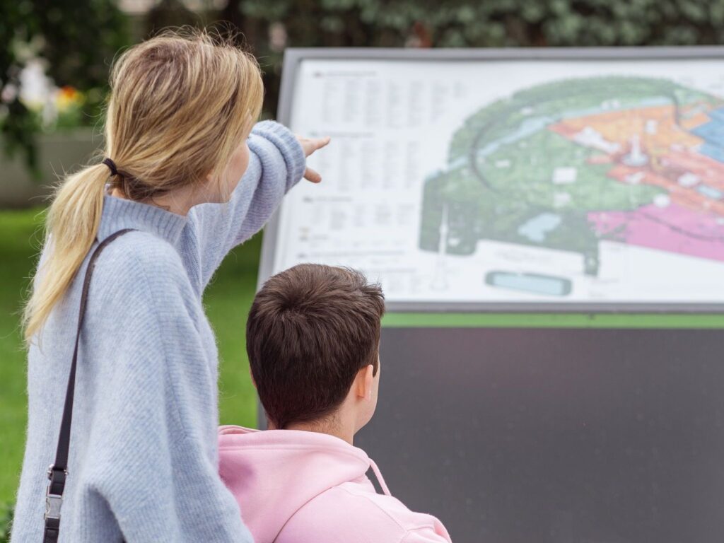 A woman pointing to a park map while a young person beside her looks on