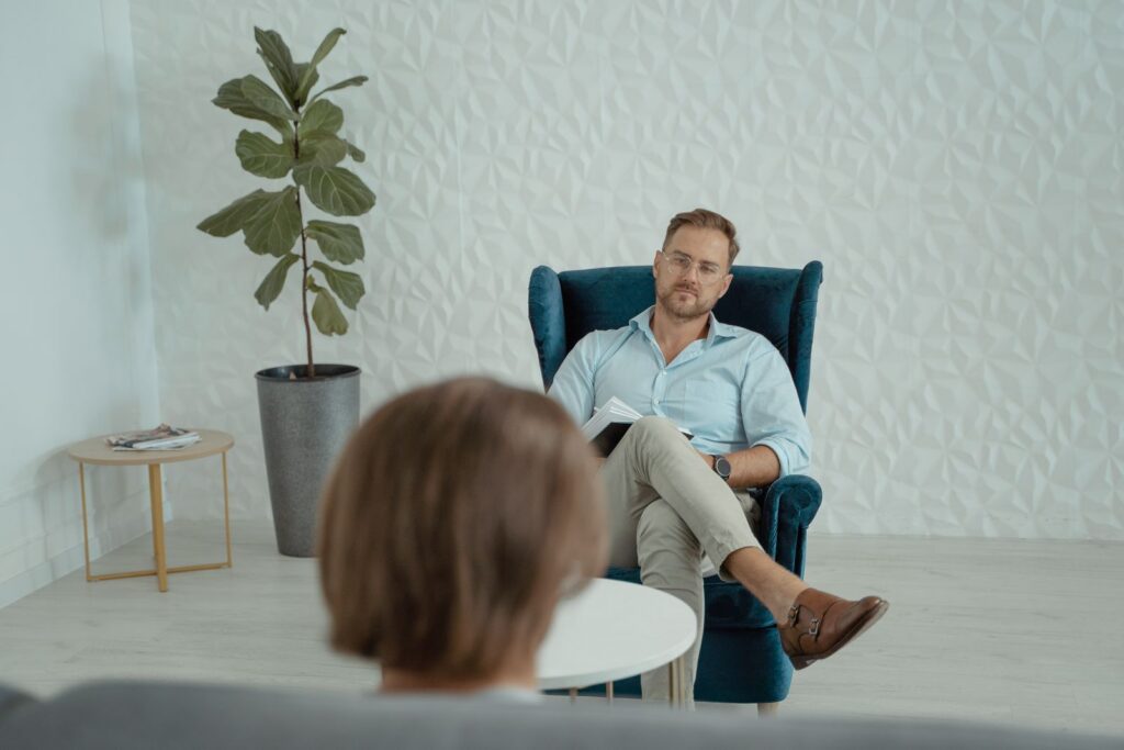 A psychologist sitting in an armchair during a calm counselling session in a bright room