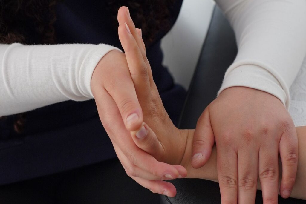 A therapist supporting and gently stretching a patient's hand during a hand therapy session