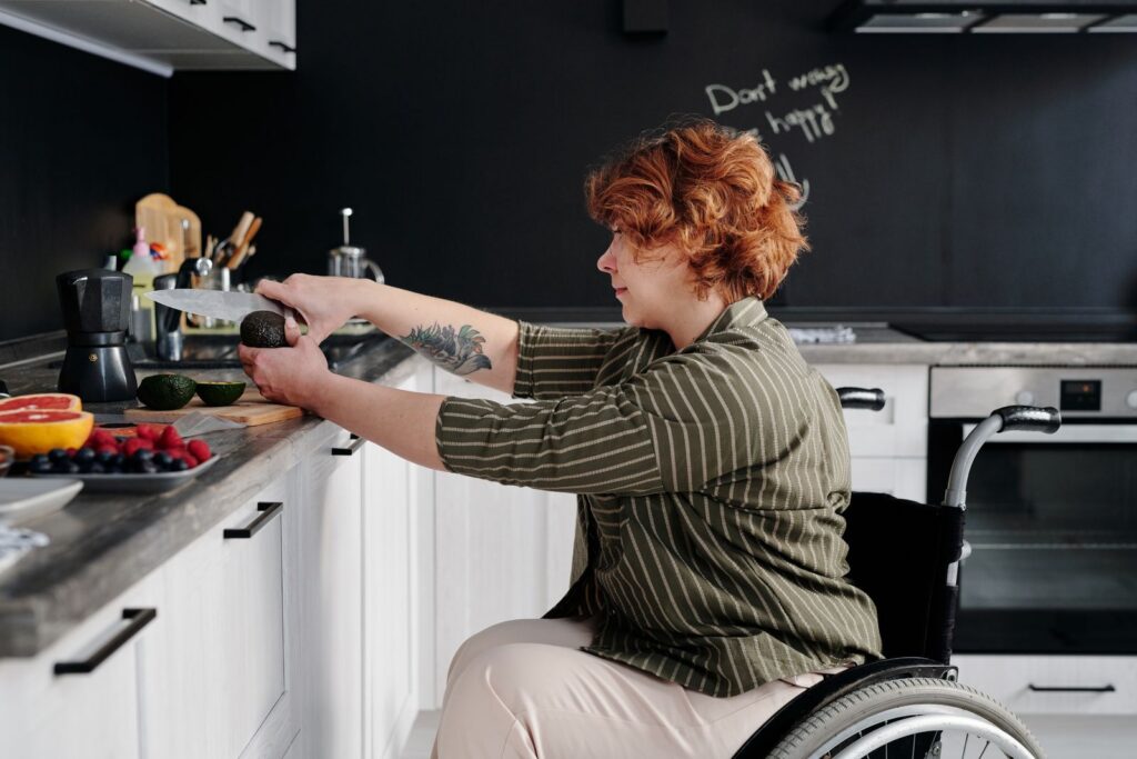 A woman in a wheelchair preparing food at a kitchen bench